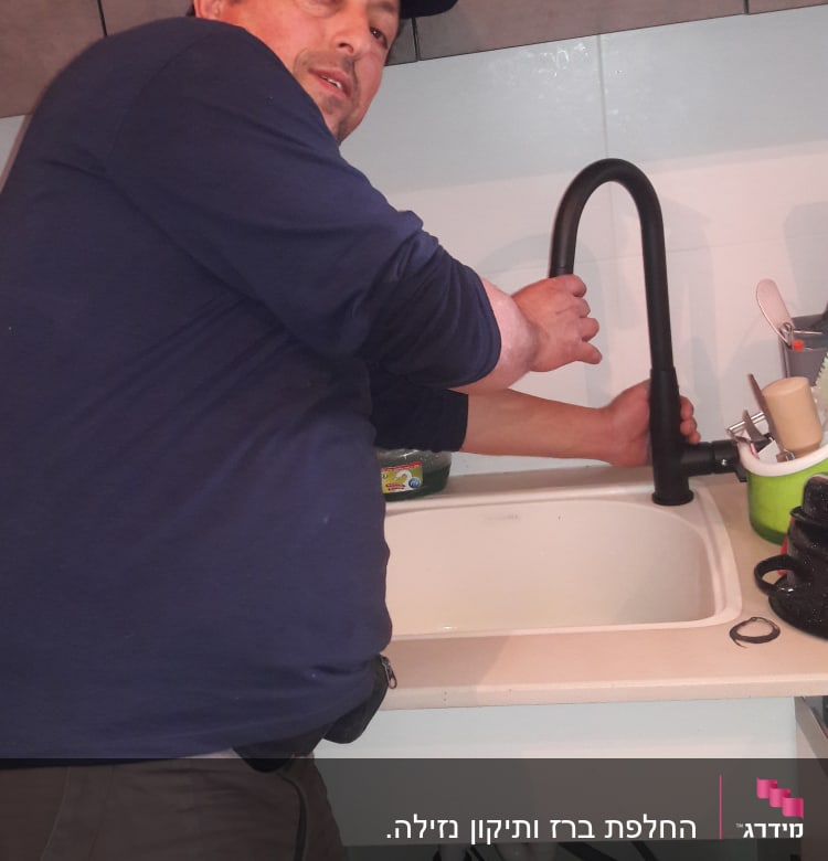 אדם מתקין ברז שחור בכיור מטבח
